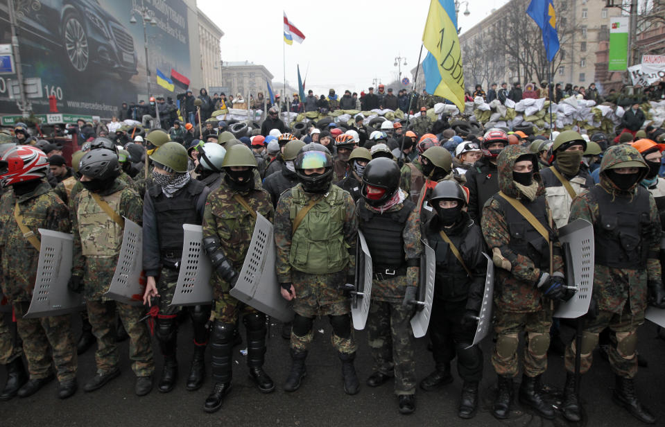 FILE - In this file photo taken on Saturday, Feb. 8, 2014, pro-European Union activists stand in front of a barricade of their tent camp to anti-government protect it in downtown Kiev, Ukraine. (AP Photo/Sergei Chuzavkov, File)