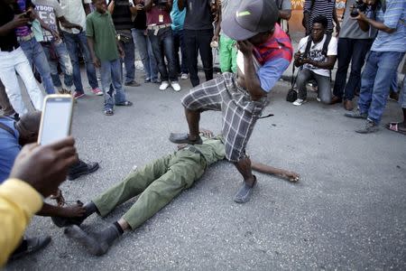 A man steps on an unidentified man in military style clothes who was stoned to death by a mob of protesters in Port-au-Prince, Haiti, February 5, 2016. REUTERS/Andres Martinez Casares