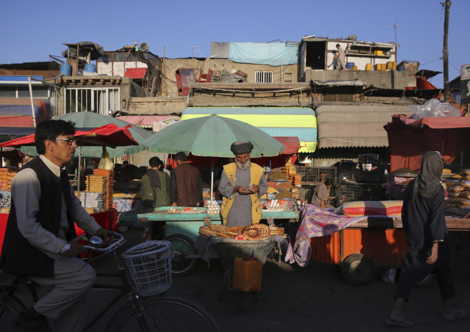 A roadside bread seller counts money as he waits for customers at a market in Kabul, Afghanistan, Tuesday, Aug. 6, 2019. (AP Photo/Rafiq Maqbool)