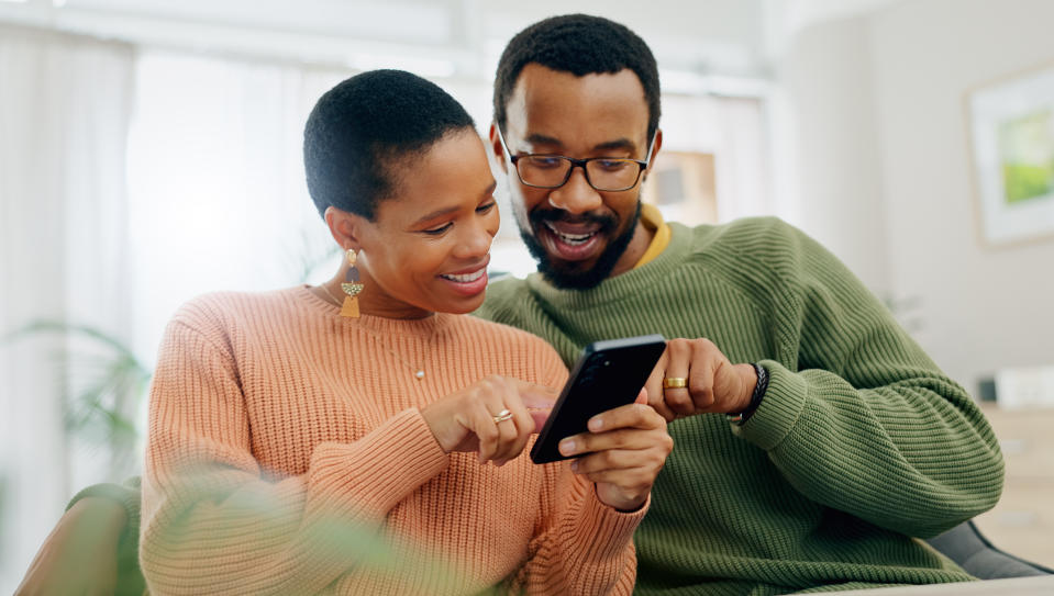 Phone, happy and black couple on sofa online for social media, internet and browse website. Love, dating and man and woman on smartphone for bonding, relationship and relax together in living room