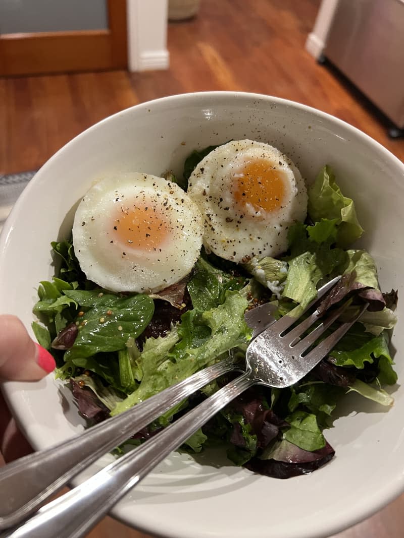 A white bowl holding a salad with eggs