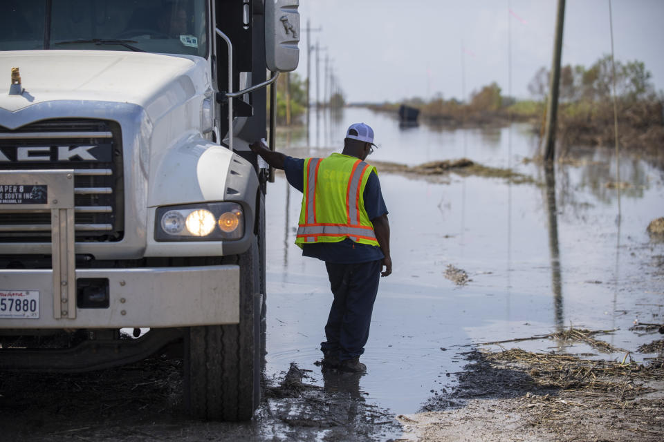 Crews work on building a sandbag levee and draining a street along Highway 23 in Plaquemines Parish, La., a week after Hurricane Ida, Tuesday, Sept. 7, 2021. (Chris Granger/The Times-Picayune/The New Orleans Advocate via AP)