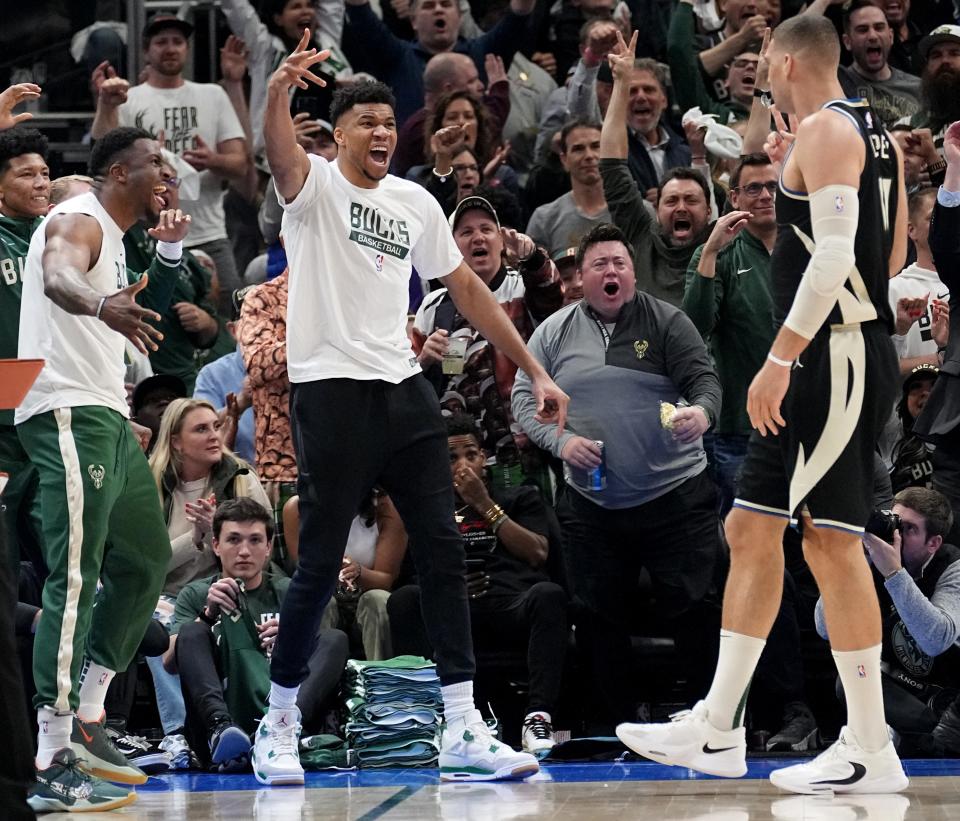 Injured Milwaukee Bucks forward Giannis Antetokounmpo, center, celebrates center Brook Lopez (11) drawing a foul during the first half of their game Wednesday against the Miami Heat.