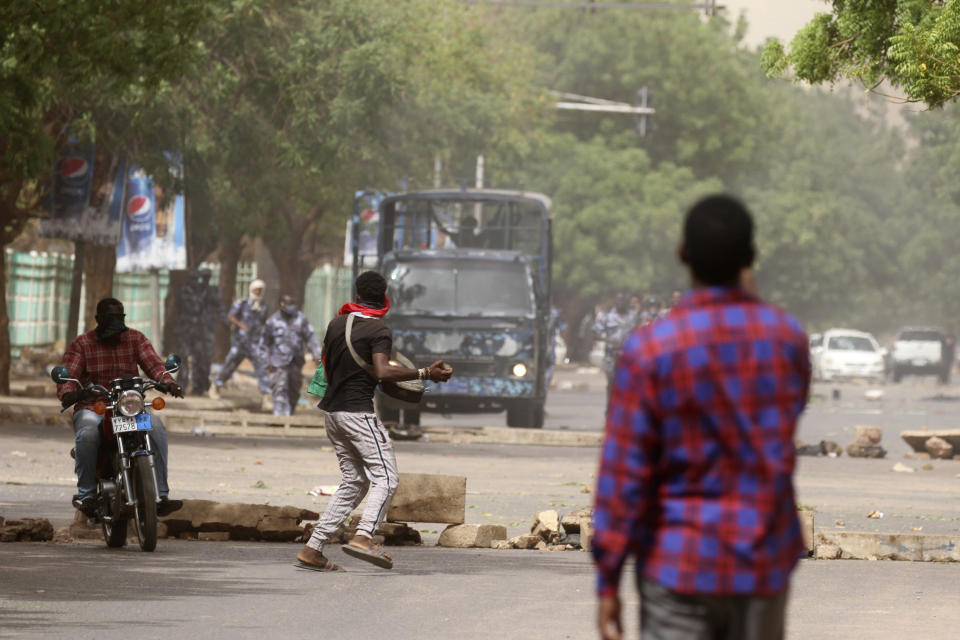 A man throws a stone towards police during a protest over economic conditions, in Khartoum, Sudan, Wednesday, June 30, 2021. The World Bank and the International Monetary Fund said in a joint statement Tuesday, that Sudan has met the initial criteria for over $50 billion in foreign debt relief, another step for the East African nation to rejoin the international community after nearly three decades of isolation. (AP Photo/Marwan Ali)