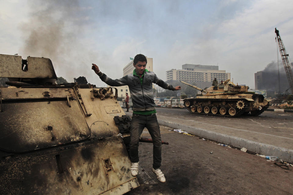 FILE - In this Jan. 29, 2011 file photo, a protester jumps from a burned armored personnel carrier in Tahrir Square, Cairo, Egypt. The 2011 uprising led to the quick ouster of autocrat Hosni Mubarak. A decade later, thousands are estimated to have fled abroad to escape a state, headed by President Abdel Fattah el-Sissi, that is even more oppressive. (AP Photo/Lefteris Pitarakis, File)