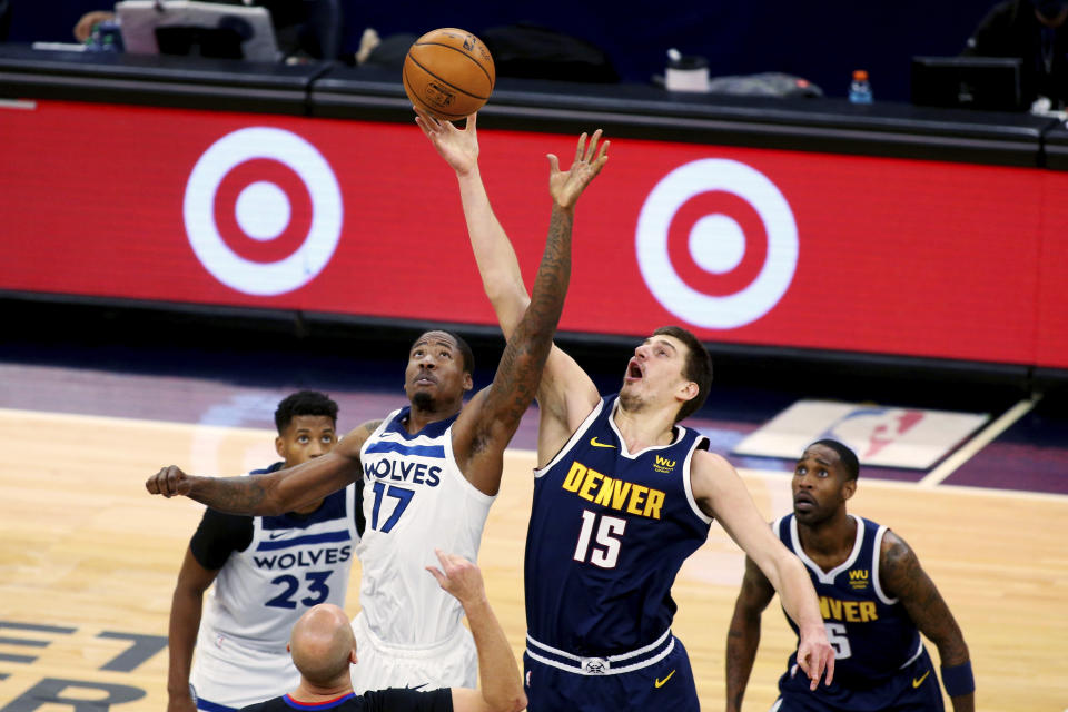 Denver Nuggets center Nikola Jokic (15) and Minnesota Timberwolves center Ed Davis (17) have a jump ball after a foul call in the first quarter of an NBA basketball game, Sunday, Jan. 3, 2021, in Minneapolis. (AP Photo/Andy Clayton-King)