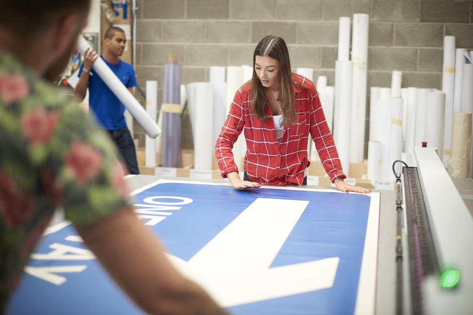 A person stands over a large, blue banner sign