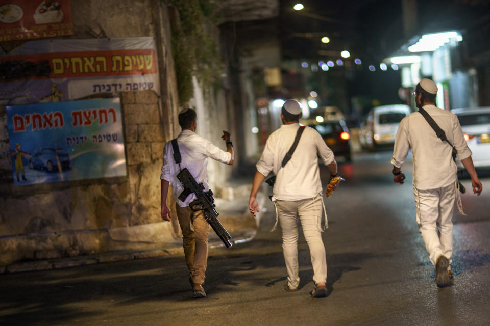 Jews walk through the street with guns in the mixed Arab-Jewish town of Lod, central Israel, Friday, May 28, 2021, in the wake of recent clashes between the two groups. During the unrest, Arab attackers targeted property belonging to the religious nationalist community. In response, armed West Bank settlers and other ultranationalists mobilized to Lod, fanning the flames. (AP Photo/David Goldman)