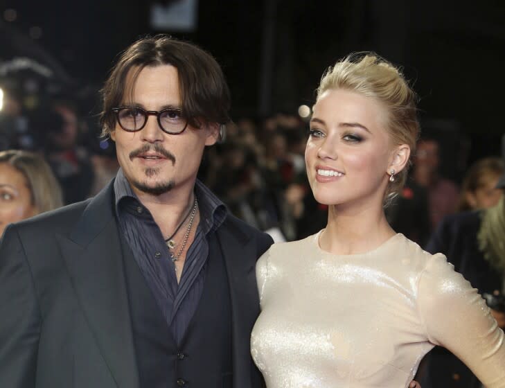 A man in a suit and a woman in a metallic dress arrive at a movie premiere