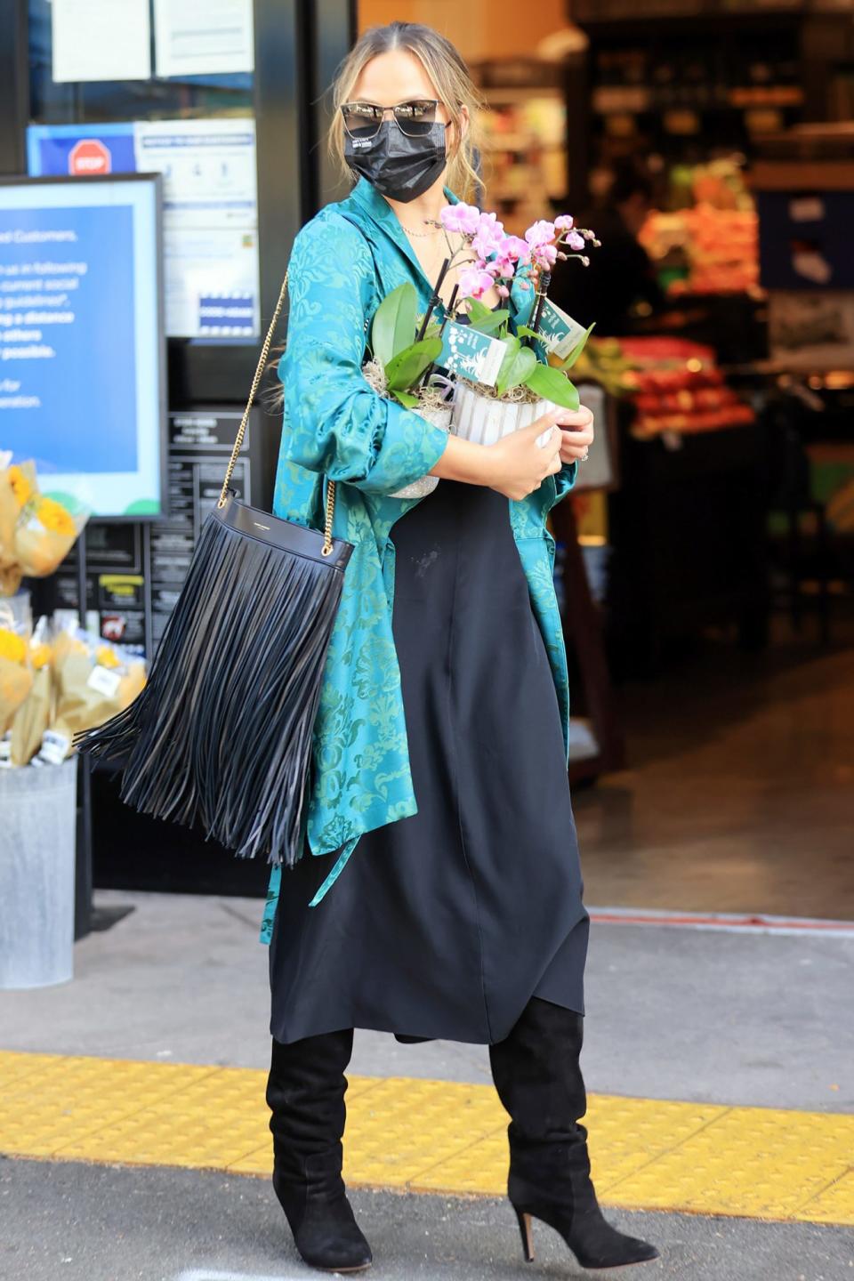 <p>Chrissy Teigen picks up some flowers while shopping in L.A. with her mom on Monday. </p>