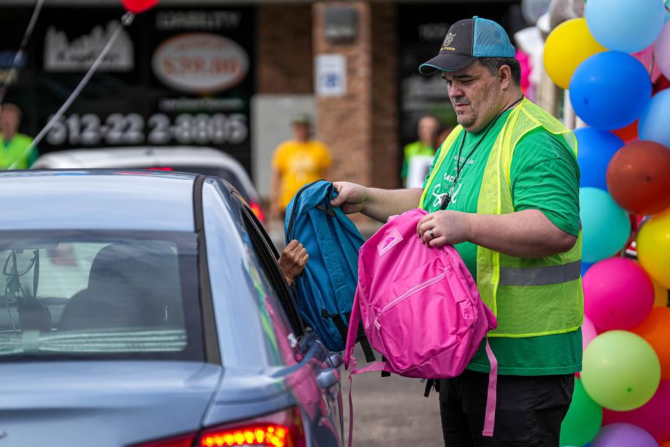 Josh Jackson, a volunteer, hands out bags at Sanchez Law Firm’s third annual back-to-school backpack drive July 27.