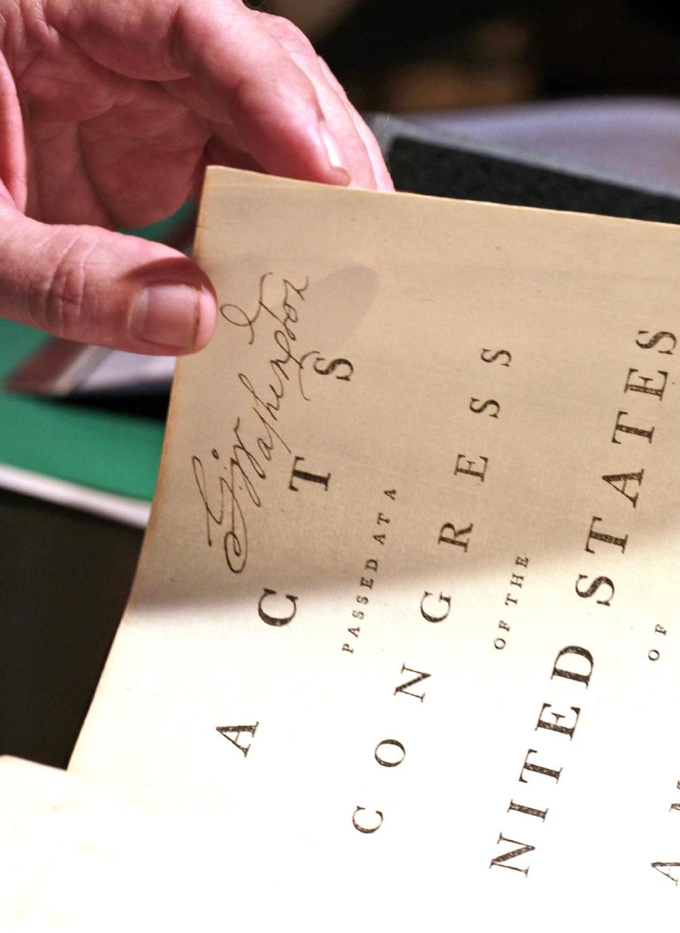 George Washington's signature is seen as Chris Coover, senior specialist for rare books & manuscripts at Christie's shows President George Washington's personal copy of the Acts of the first Congress (1789), containing the U.S. Constitution and the proposed Bill of Rights, during a media availability, Tuesday, June 12, 2012, in Washington. The book will go on auction June 22nd and is expected to bring between $2-3 million. (AP Photo/Alex Brandon)