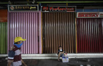 In this April 10, 2020, photo, a cigarette vendor sits near rows of shops closed due to coronavirus outbreak at a market in Jakarta, Indonesia. While its neighbors scrambled early this year to try to contain the spread of the new coronavirus, the government of the world’s fourth most populous nation insisted that everything was fine. Only after the first cases were confirmed in March did President Joko Widodo acknowledge that his government was deliberately holding back information about the spread of the virus to prevent the public from panicking. The country now has the the highest death toll in Asia after China. (AP Photo/Dita Alangkara)