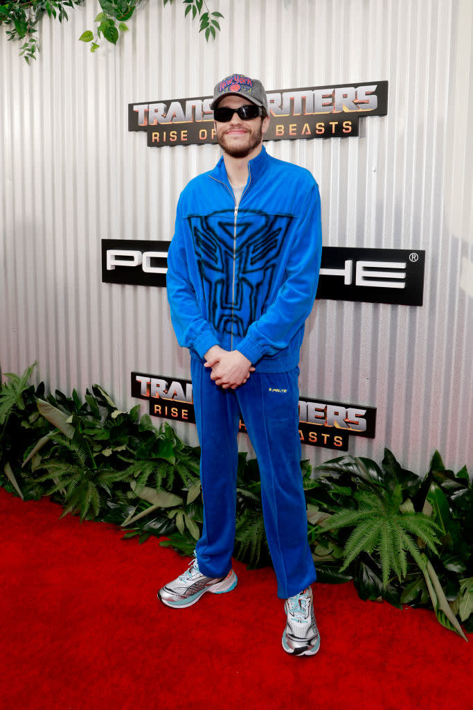 Man in blue tracksuit with logo, sunglasses, and sneakers at Transformers premiere