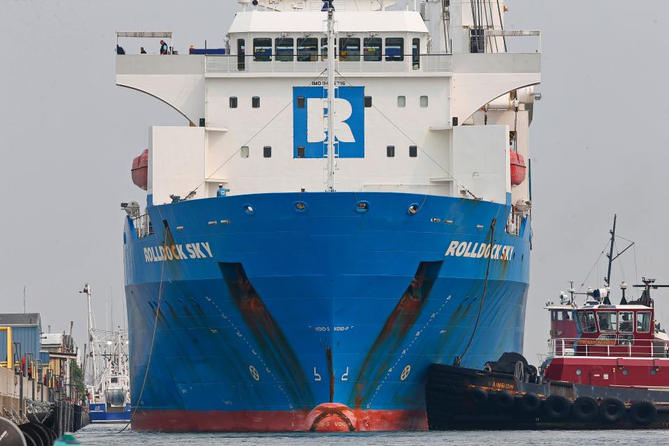 A tugboat helps a ship carrying wind turbine blades for Vineyard Wind to dock at the New Bedford Marine Commerce Terminal