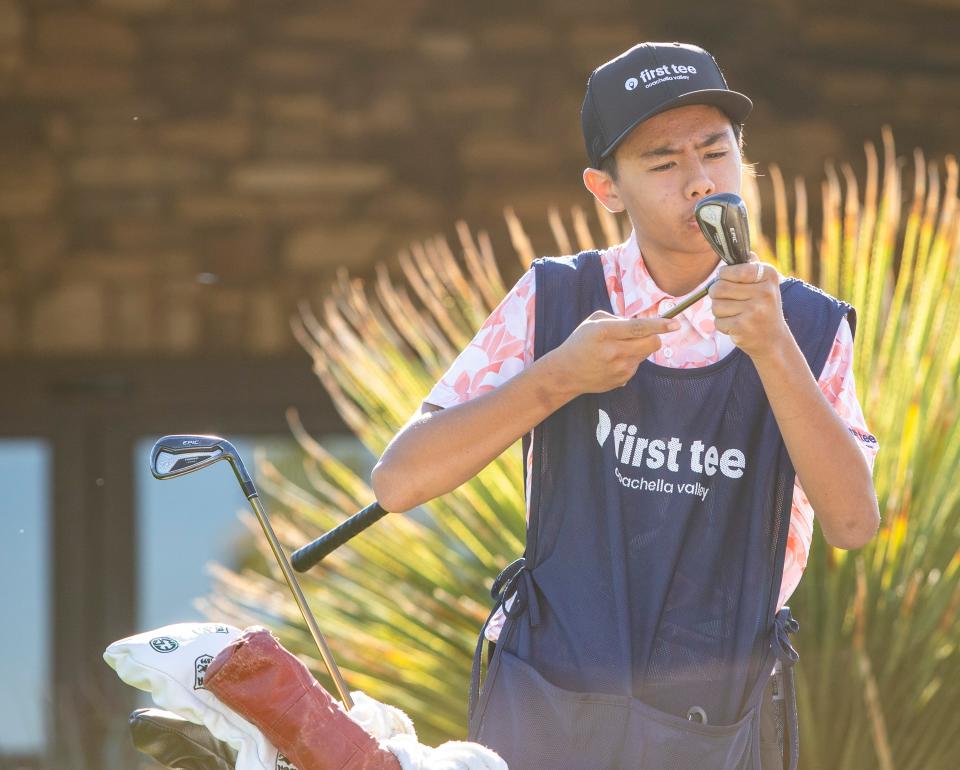 First Tee caddie Brighton Cariaga, 14, cleans his assigned golfer's clubs while waiting for their tee time on hole one at Ironwood Country Club in Palm Desert, Calif., Saturday, Nov. 18, 2023.