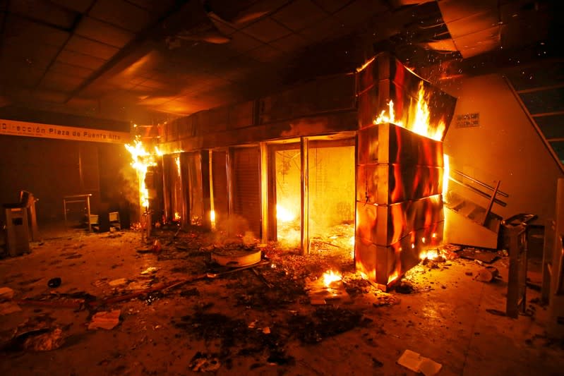 A subway ticket office is seen on fire during a protest against the increase in the subway ticket prices in Santiago