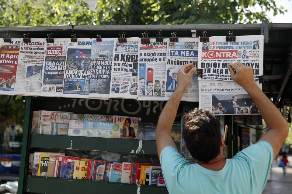 A vendor adjusts the front pages of the Greek newspapers as all of them refer to the election result in Athens, Monday, July 8, 2019. Conservative party leader Kyriakos Mitsotakis' New Democracy party won 39.8% of the Sunday vote, giving him 158 seats in the 300-member parliament, a comfortable governing majority. (AP Photo/Thanassis Stavrakis)