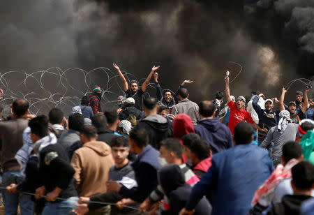 Palestinian demonstrators remove the Israeli barbed wire during clashes with Israeli troops at a protest demanding the right to return to their homeland, at the Israel-Gaza border, east of Gaza City, April 27, 2018. REUTERS/Mohammed Salem