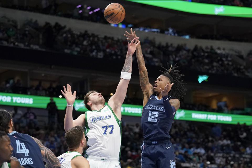 Dallas Mavericks guard Luka Doncic (77) defends as Memphis Grizzlies guard Ja Morant (12) shoots in the first half of an NBA basketball game in Dallas, Sunday, Jan. 23, 2022. (AP Photo/Tony Gutierrez)