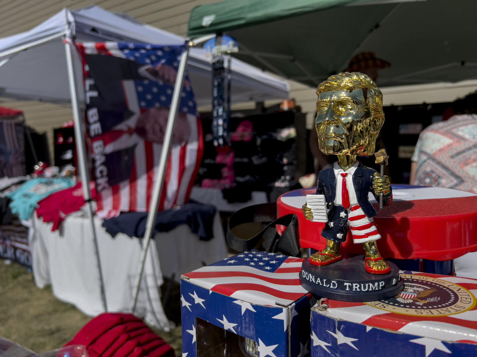 A gold-colored bobblehead of former President Donald Trump and other merchandise is displayed for sale during the ReAwaken America Tour at Cornerstone Church in Batavia, N.Y., Saturday, Aug. 13, 2022. Since early 2021, the ReAwaken America Tour has carried its message of a country under siege to tens of thousands of people in 15 cities and towns. It serves as a traveling roadshow and recruiting tool for an ascendant Christian Nationalist movement that has grown in power and influence inside the Republican Party. (AP Photo/Carolyn Kaster)