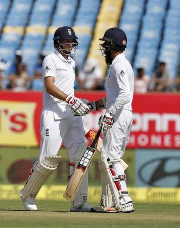 Cricket - India v England - First Test cricket match - Saurashtra Cricket Association Stadium, Rajkot - 9/11/16. England's Joe Root (L) is congratulated by his teammate Moeen Ali after scoring his half century. REUTERS/Amit Dave