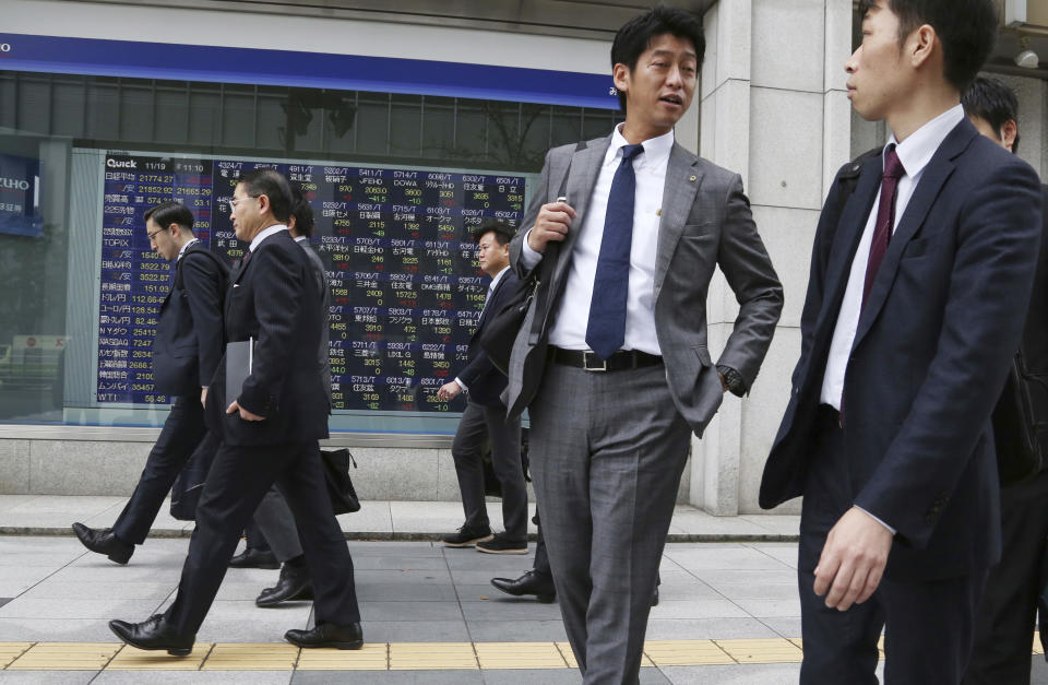 People walk by an electronic stock board of a securities firm in Tokyo, Monday, Nov. 19, 2018. Asian shares were mostly higher Monday after a buying spree on Wall Street kept up investor optimism into a new week, despite continuing worries about trade tensions. (AP Photo/Koji Sasahara)