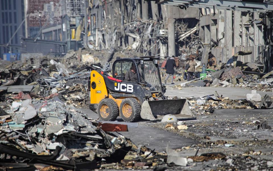 A driver operates a bucket loader to remove rubble from the premises of a shopping mall ruined as a result of a missile strike carried out by Russian troops - Yuliia Ovsiannikova / Ukrinform/Future Publishing