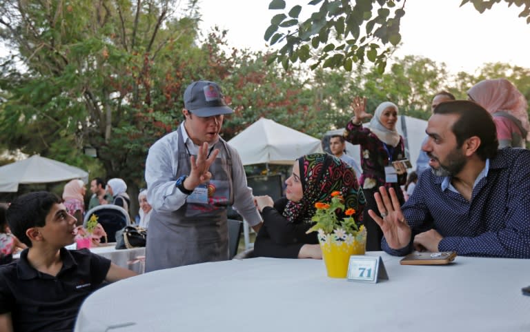 Abdel Rahman, a 21-year-old with Down's Syndrome, serves customers at the Succet cafe in Damascus on July 11, 2018