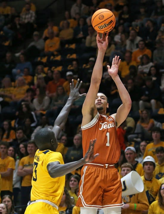 Texas forward Dylan Disu (1) is defended by West Virginia forward Akok Akok (13) during the first half of an NCAA college basketball game on Saturday, Jan. 13, 2024, in Morgantown, W.Va. (AP Photo/Kathleen Batten)