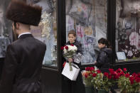 Girls buy flowers from a sidewalk flower stand on the first day of Passover, Wednesday, April 8, 2020 in the Williamsburg neighborhood of New York during the coronavirus pandemic. (AP Photo/Mark Lennihan)