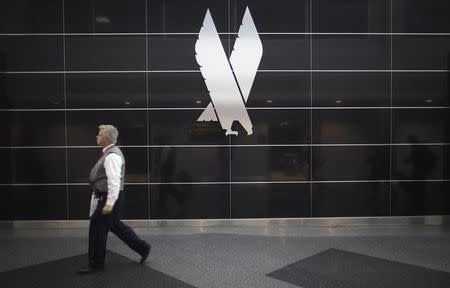 A man walks past an American Airlines logo on a wall at John F. Kennedy (JFK) airport in in New York November 27, 2013. REUTERS/Carlo Allegri