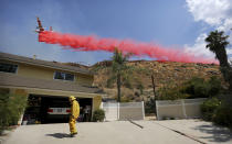 <p>Riverside City Fire Department Engineer Peter Habib stands outside a home to help provide structure protection as a plane drops fire retardant on a hillside during the Marlborough fire on Thursday, Aug. 31, 2017 in Riverside, Calif. (Photo: Stan Lim/The Press-Enterprise via AP) </p>