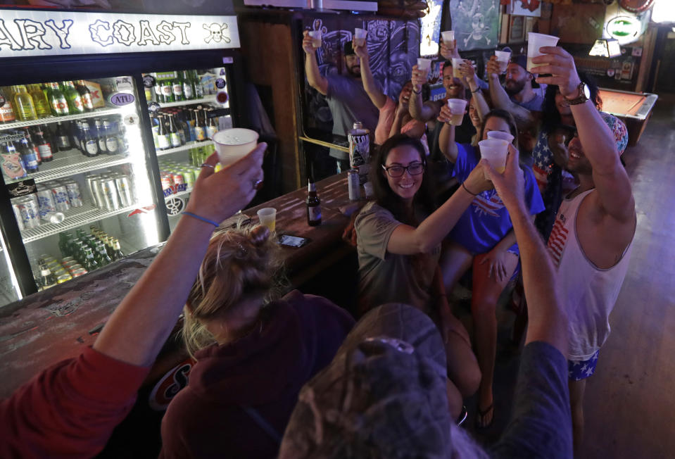 Locals riding out the storm toast Hurricane Florence as they relax at the Barbary Coast bar in downtown Wilmington, N.C., as the Florence threatens the coast Thursday, Sept. 13, 2018. (AP Photo/Chuck Burton)