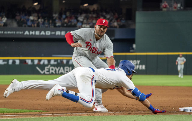 Philadelphia Phillies first baseman Darick Hall, top, tags out Texas Rangers' Nathaniel Lowe, bottom, at first base during the fourth inning of an opening day baseball game, Thursday, March 30, 2023, in Arlington, Texas. (AP Photo/Jeffrey McWhorter)