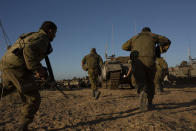 Israeli soldiers run for cover under armored vehicles as a siren sounds warning of incoming rockets fired from Gaza strip in a staging area near the Israeli-Gaza border southern Israel, Saturday, May 15, 2021. (AP Photo/Maya Alleruzzo)a