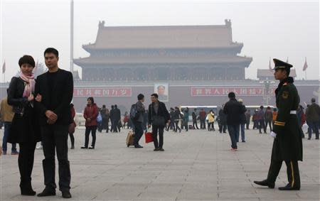 A paramilitary soldier patrols near visitors posing for souvenir pictures at Tiananmen Square in Beijing, November 1, 2013. REUTERS/Kim Kyung-Hoon
