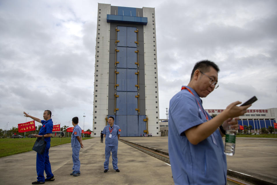 Workers gather near a building at the Wenchang Space Launch Site in Wenchang in southern China's Hainan province, Monday, Nov. 23, 2020. Chinese technicians were making final preparations Monday for a mission to bring back material from the moon's surface for the first time in nearly half a century — an undertaking that could boost human understanding of the moon and of the solar system more generally. (AP Photo/Mark Schiefelbein)