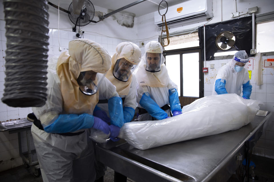 Workers from "Hevra Kadisha," Israel's official Jewish burial society, prepare a body before a funeral procession at a special morgue for people who died from COVID-19, during a nationwide lockdown to curb the spread of the coronavirus, in the central Israeli city of Holon, near Tel Aviv, Israel, Sunday, Jan. 10, 2021. (AP Photo/Oded Balilty)