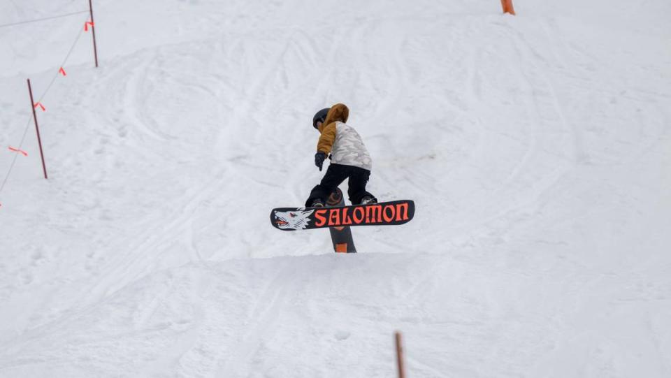 A snowboarder pops off a rail at a Palisades Tahoe terrain park on Thursday, Dec. 21, 2023. Many Tahoe-area ski resorts have limited runs open due to a lack of snowfall and warmer temperatures.