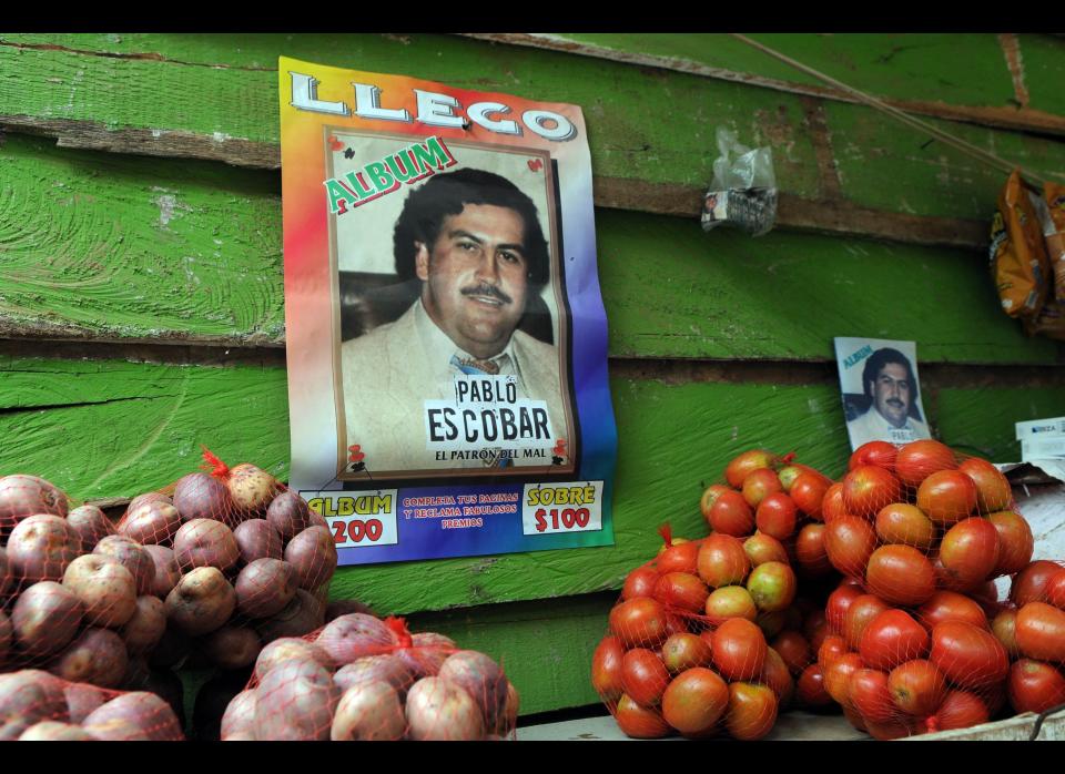 A poster promoting a magazine style publication about the life of the late Colombian drug trafficker Pablo Escobar hangs on the wall of small food store in the neighborhood Comuna Nororiental 1 in Medellin, Colombia, Wednesday, Aug. 8, 2012. The magazine, whose publisher is unknown, comes with blank pages with instructions to fill them with small photographs which are bought separately, like baseball cards, at several small stores in this neighborhood. The cards showing images of Escobar, are a mix of real life photos and of actors playing out his life from a local TV series called "Escobar, El Patrón del Mal." (AP Photo/Luis Benavides)