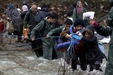 Refugees and migrants attempt to cross a river near the Greek-Macedonian border to enter Macedonia after an unsuccessful attempt yesterday, west of the village of Idomeni, Greece, March 15, 2016. REUTERS/Alexandros Avramidis