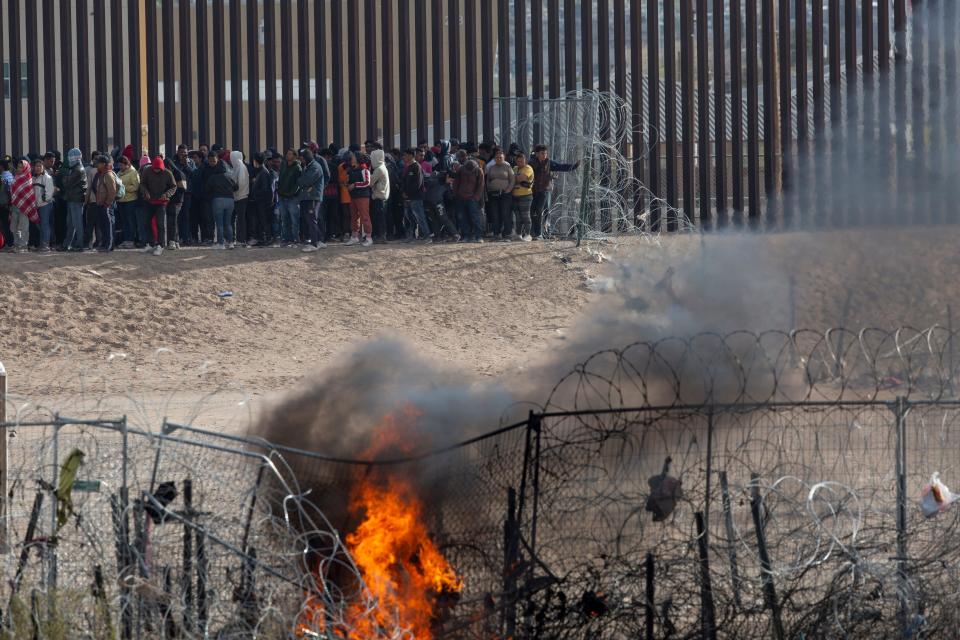 Hundreds of migrants line up along the border wall in El Paso after they breached razor wire barriers Thursday.