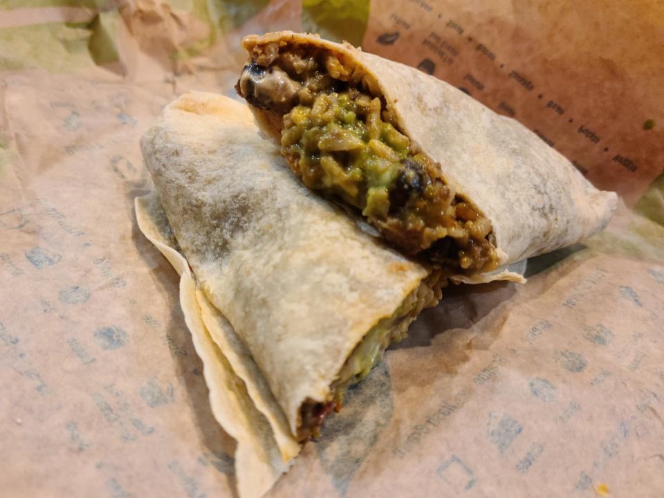 fiesta veggie burrito from taco bell cut in half and resting on a paper wrapper