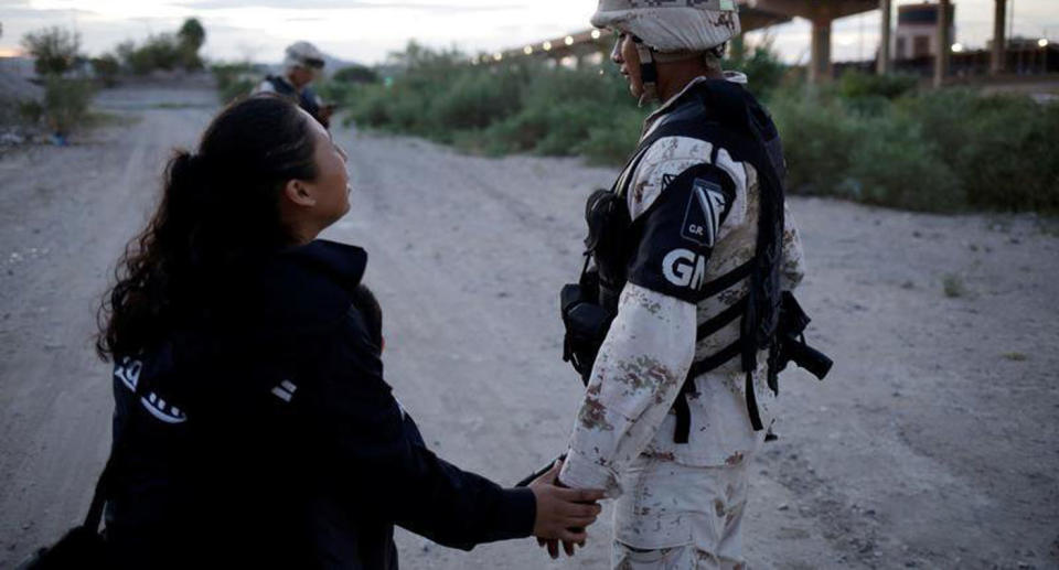 A Reuters photographer captured the photos. Seen here is the mother taking a National Guard soldier's hand, pleading with him to let her and her son cross the border.