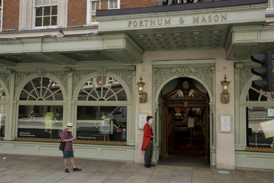 A doorman wearing a face shield and mask to protect from coronavirus stands outside the main entrance of the Fortnum & Mason department store in the Piccadilly area of central London, Friday, May 22, 2020. The store reopened its food hall department for customers to enter yesterday as part of a phased reopening as the British government is beginning to relax aspects of its nationwide coronavirus lockdown. (AP Photo/Matt Dunham)