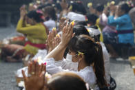 A woman wearing a face mask as a precaution against the new coronavirus outbreak during a Hindu ritual prayer at a temple in Bali, Indonesia on Wednesday, Sept. 16, 2020. (AP Photo/Firdia Lisnawati)