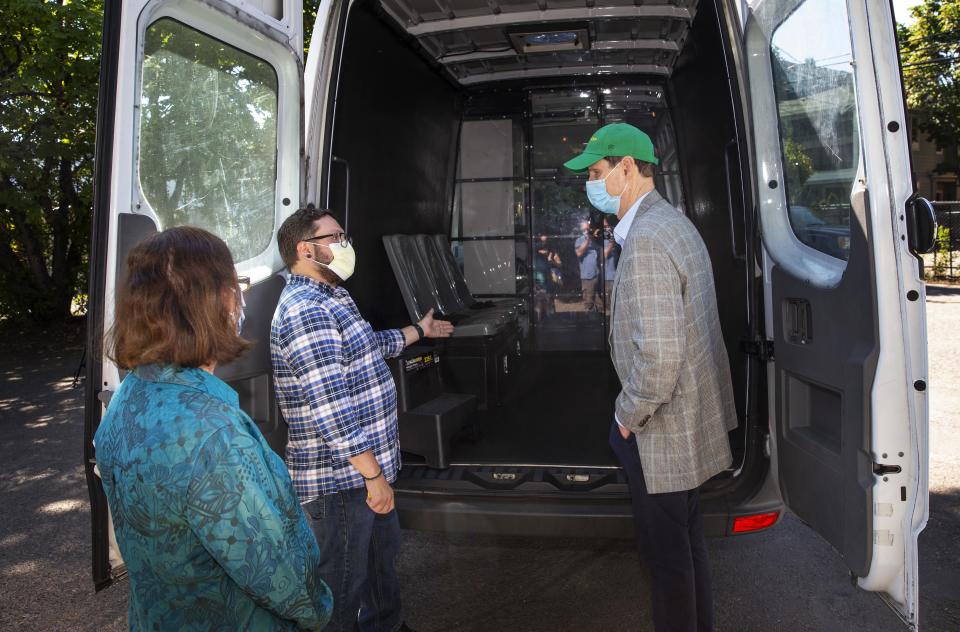 CAHOOTS operations coordinator Tim Black, center, takes Eugene Mayor Lucy Vinis, left, and U.S. Senator Ron Wyden on a tour of one of the program's vans in August 2020.