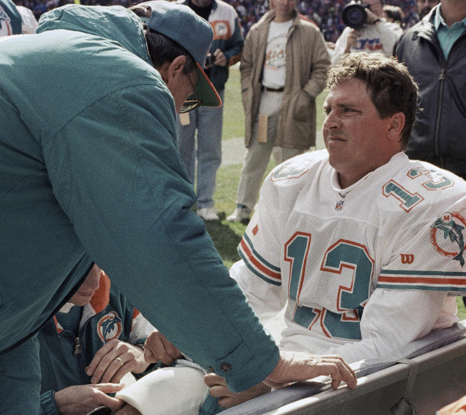 FILE - Dan Marino (13) of the Miami Dolphins is examined on the sidelines by the team trainer after being injured during an NFL football game against the Cleveland Browns, Oct. 10, 1993, in Cleveland. Miami had gone to the AFC title game in 1992 and was off to a 4-1 start the following season when Marino went down with a season-ending Achilles injury. (AP Photo/Jeff Glidden, File)