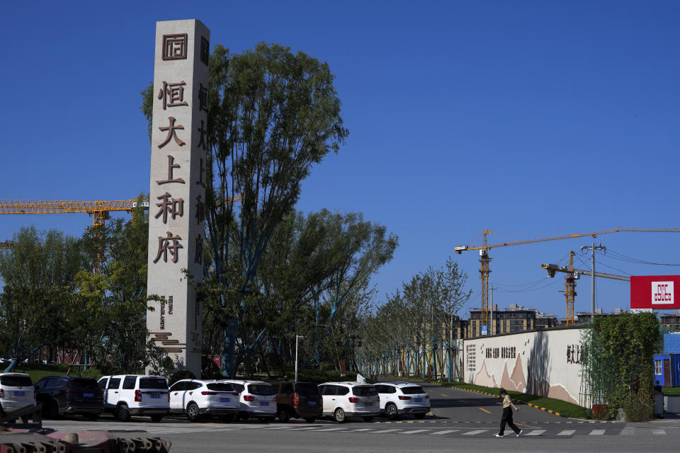 A woman walks by an Evergrande new housing development in Beijing on Sept. 22, 2021. China's central bank said Friday, Oct. 15, 2021 that financial risks from China Evergrande Group's debt problems are "controllable" and unlikely to spill over, amid growing investor concerns that the crisis could ripple through other developers. (AP Photo/Andy Wong)